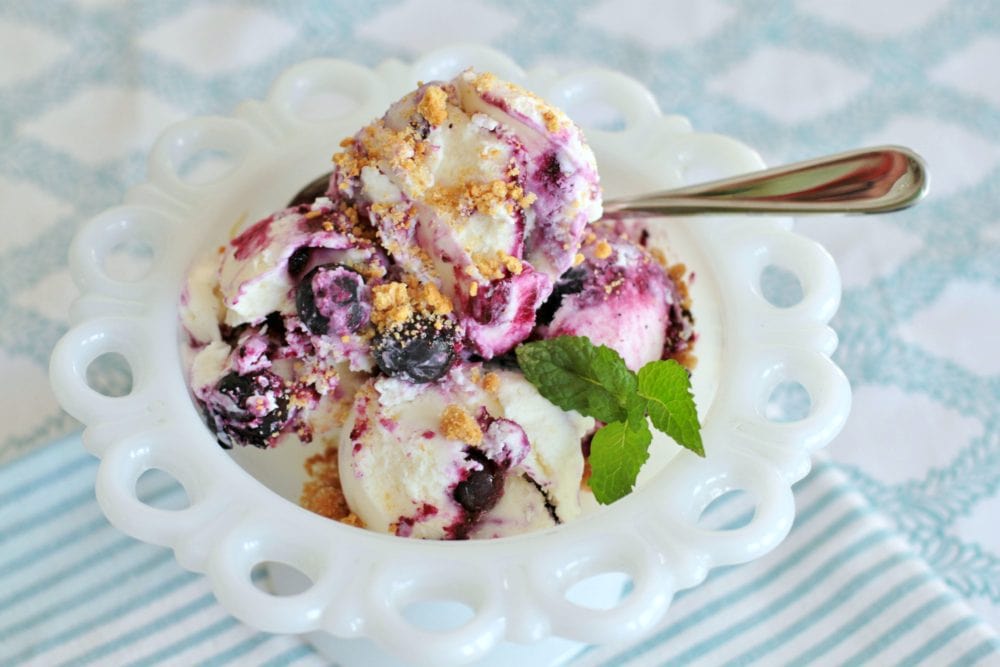 A vintage bowl filled with scoops of blueberry cheesecake ice cream.