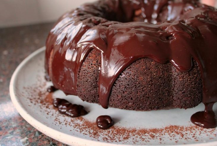 A chocolate bundt cake with glossy chocolate glaze dripping down.