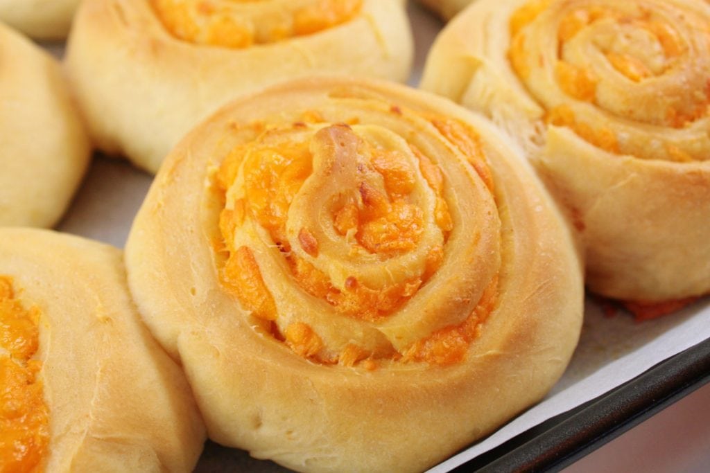 Cheesebuns -A Close up of a round scrolled bun filled with cheddar cheese. 