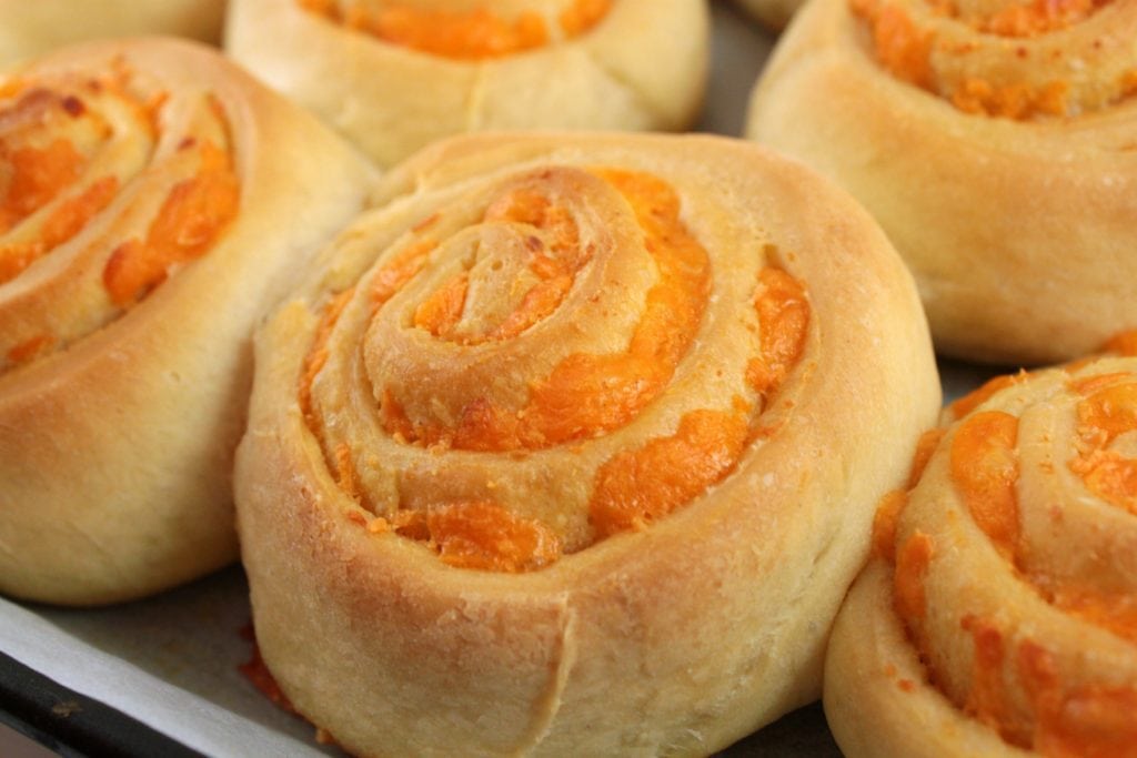 Cheesebuns - A Close up of a round scrolled bun filled with cheddar cheese. 