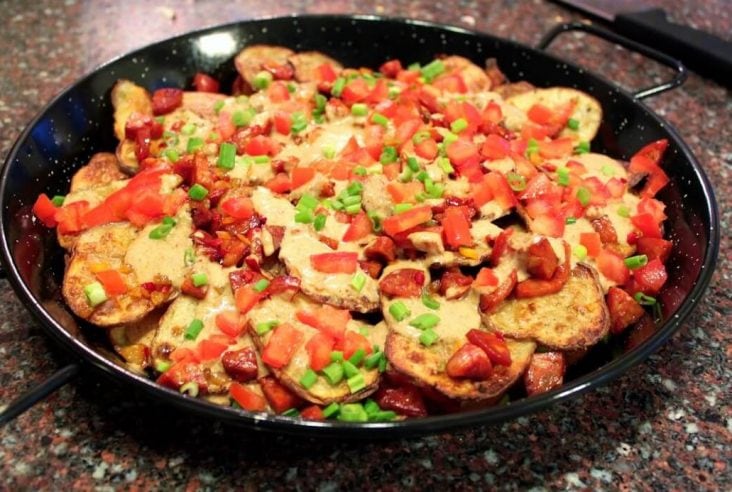 A plate of Cheesy Guinness Potato Nachos with toppings.