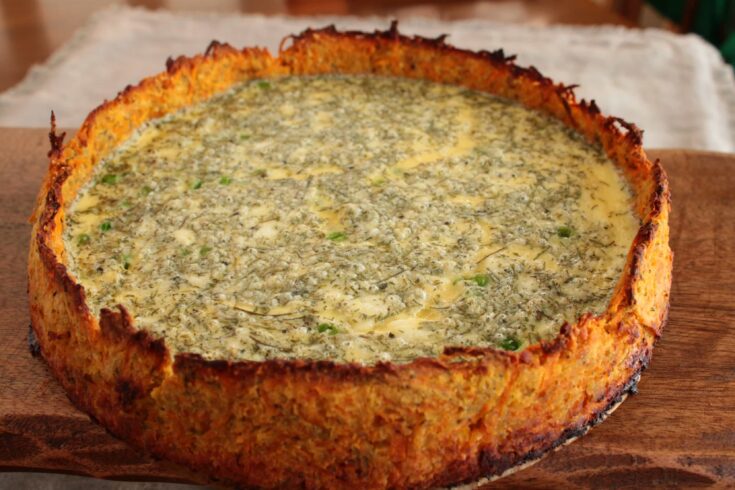 A feta cheese, pea and dill quiche in a gluten free sweet potato crust on a board.