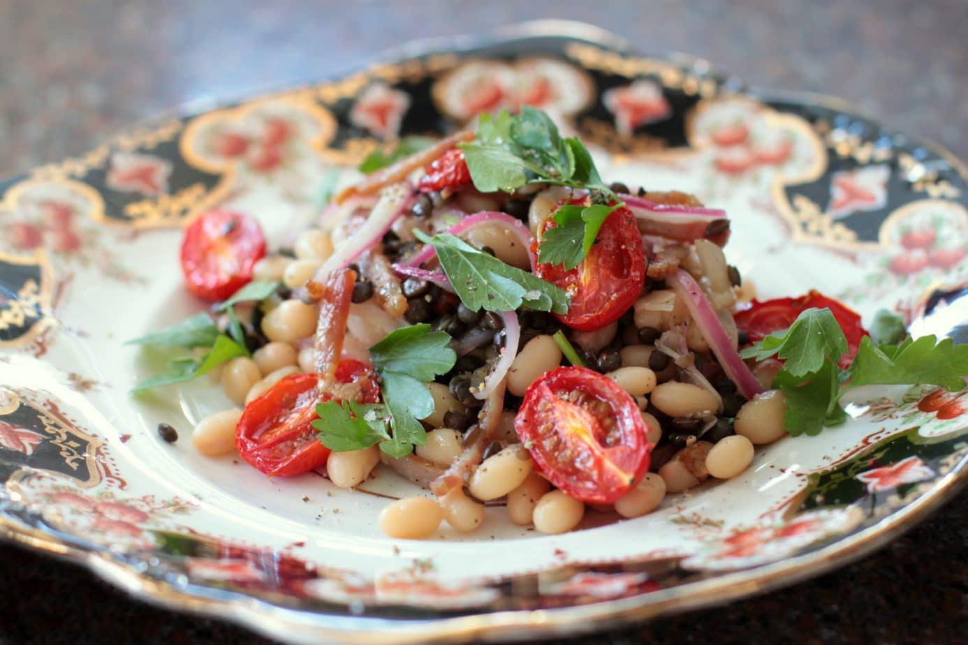 A vibrant white bean lentil and bacon salad on a vintage plate.