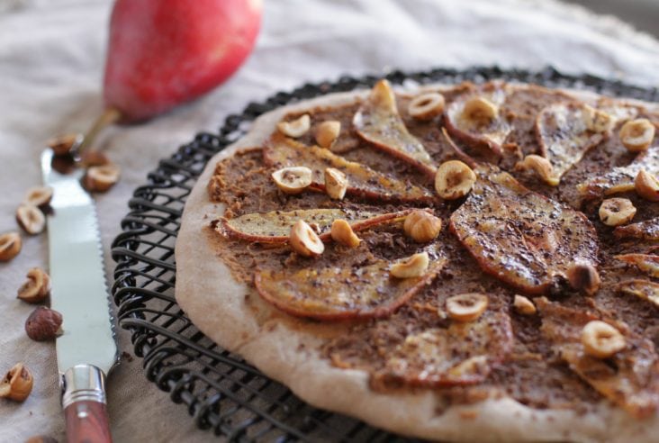 A sweetly styled and delicious sweet pizza with a chestnut flour crust and topped with candied pear, roasted hazelnuts,, and chocolate. #sweetpizza #dessertpizza #dessert #pizza