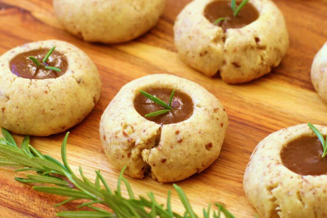 Pecan Polvorones - Caramel filled cookes topped with a sprig of green rosemary on a wooden platter.
