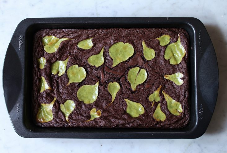 Squares of brownies on a marble background.Decadent chocolate brownies topped with little matcha cheesecake hearts.