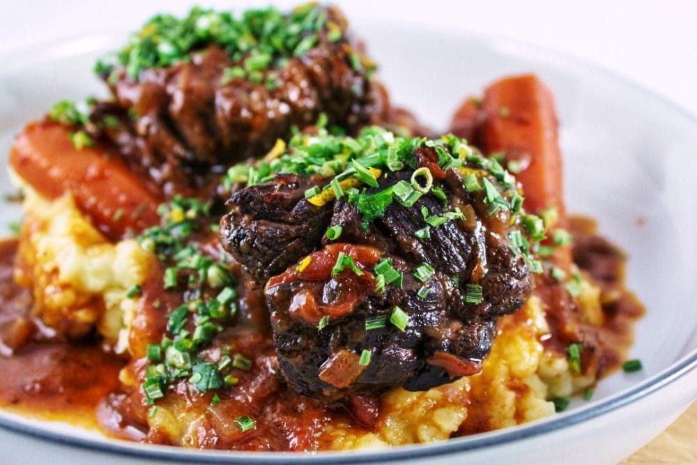Braised beef short ribs in a rich beefy gravy with carrots over top of mashed potatoes.