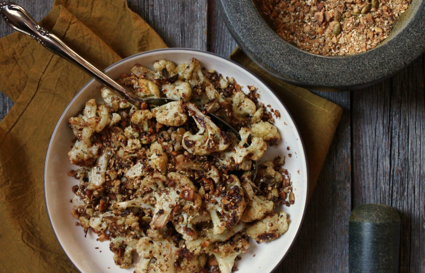 A bowl of roasted cauliflower covered in roasted dukka spices.