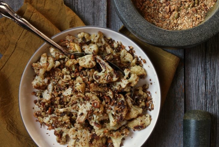 A bowl of roasted cauliflower covered in roasted dukka spices.