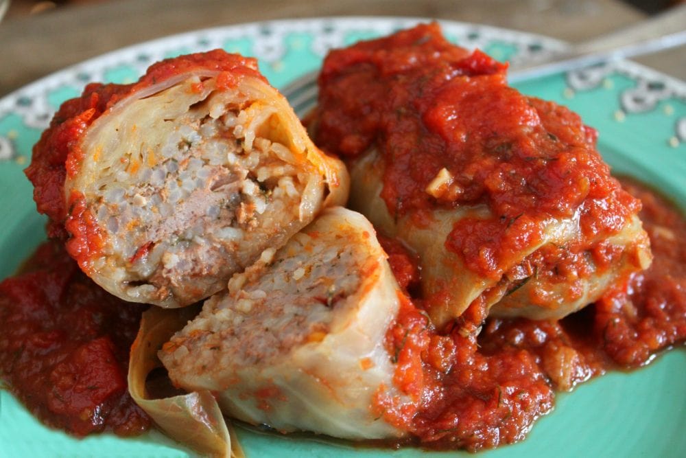 Cabbage Rolls filled with rice and meat covered in a red tomato sauce.