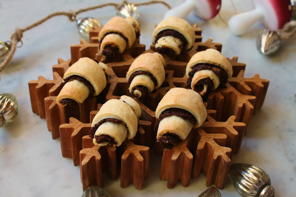 Rugelach rolled cookies sit on a wooden snowflake platter.