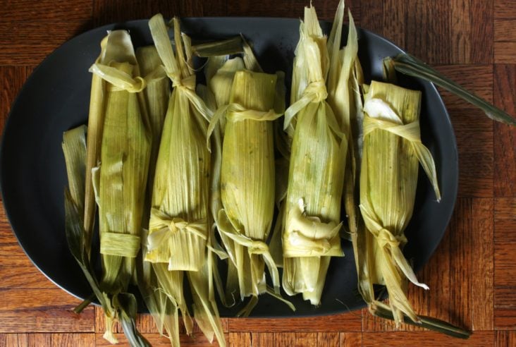 A Platter of green tamales or Steamed Tamalitos Verdes on a wooden table..