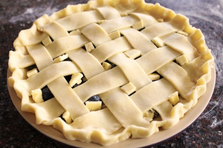 An unbaked pie with a lattice pastry top.