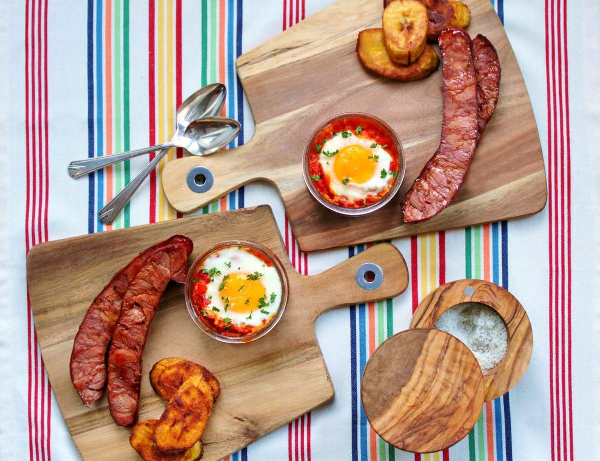 A vibrant photo featuring Huevos Habaneros, a typical Cuban breakfast of baked eggs in tomato sauce, chorizo sausage, and fried plantains.