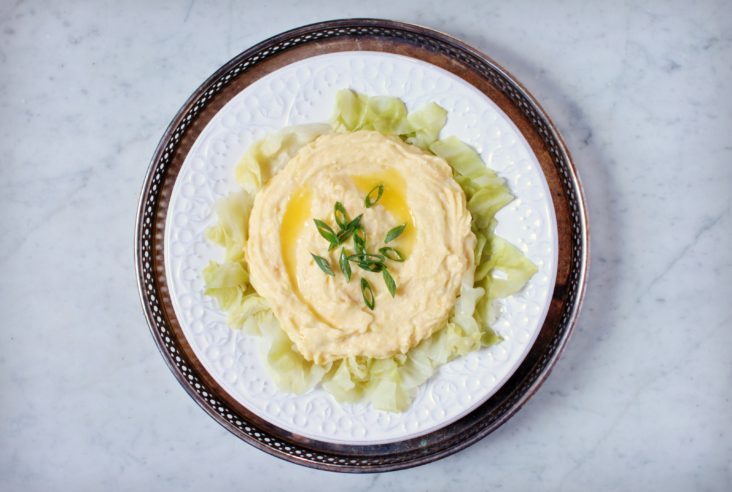 A white plate containing Irish Colcannon; mashed potatoes, cabbage, and rutabaga.