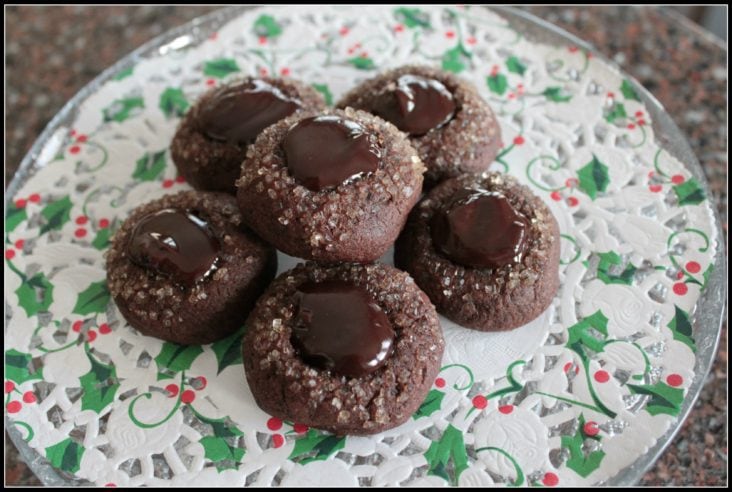 A plate full of dark chocolate cookies topped with crystal sugar and chocolate ganache.