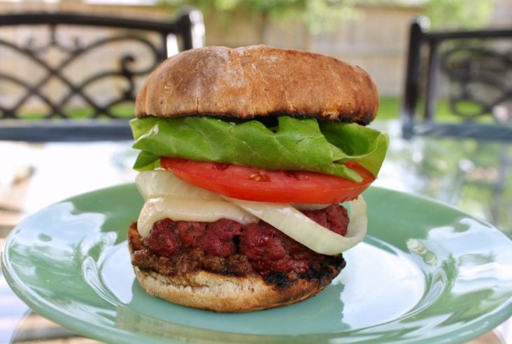 A smoked bison burger on a golden bun with lettuce, onions, tomato and cheese.