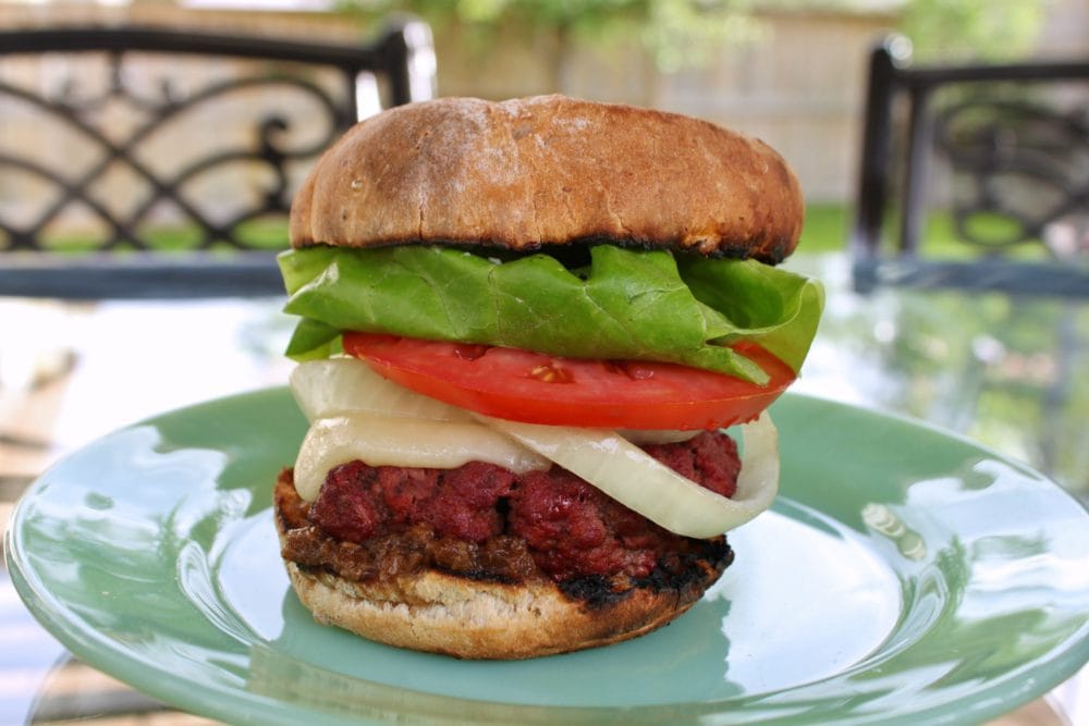 A smoked bison burger on a golden bun with lettuce, onions, tomato and cheese.
