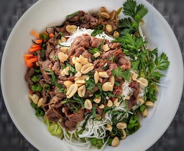 A white bowl filled with Vietnamese beef noodle salad.