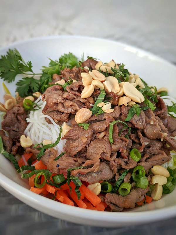 A white bowl filled with Vietnamese beef noodle salad.