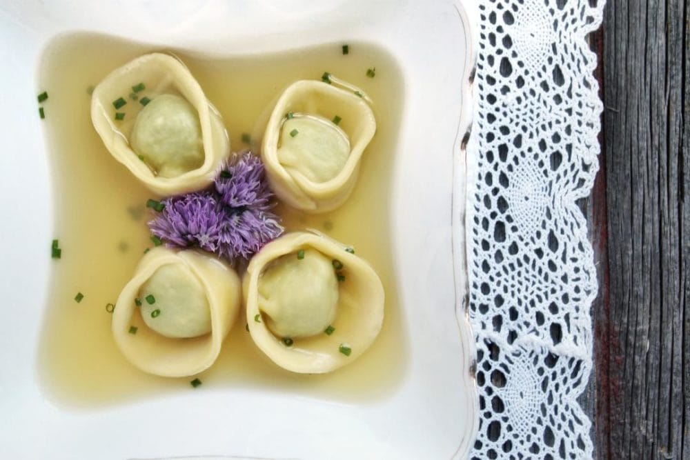 A bowl with four homemade tortellini in broth.