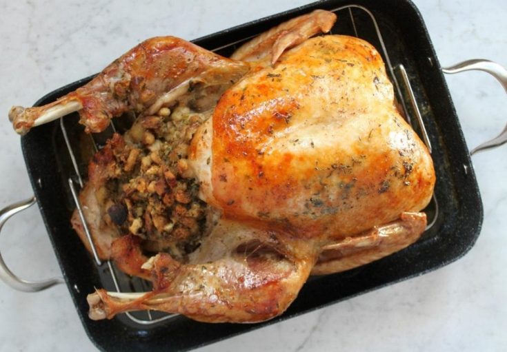 A beautiful fully cooked and stuffed in a black roasting pan.