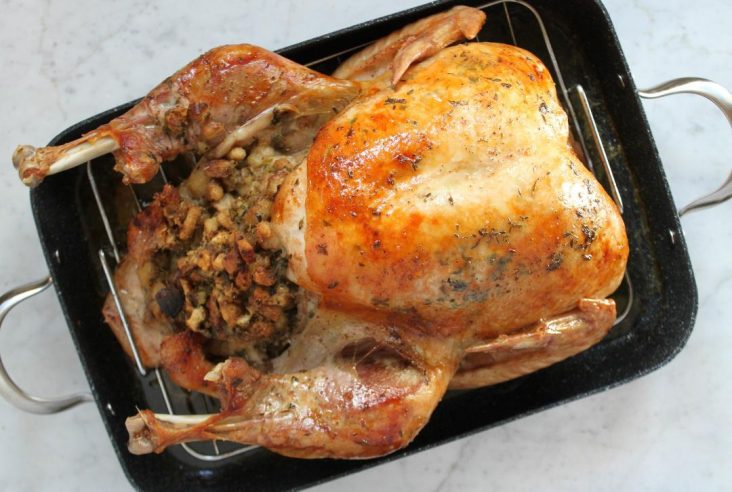 Best Ever Turkey Brine Recipe - Dish 'n' the Kitchen Pin image of a perfectly browned roasted, and stuffed Turkey in a black roasting pan.