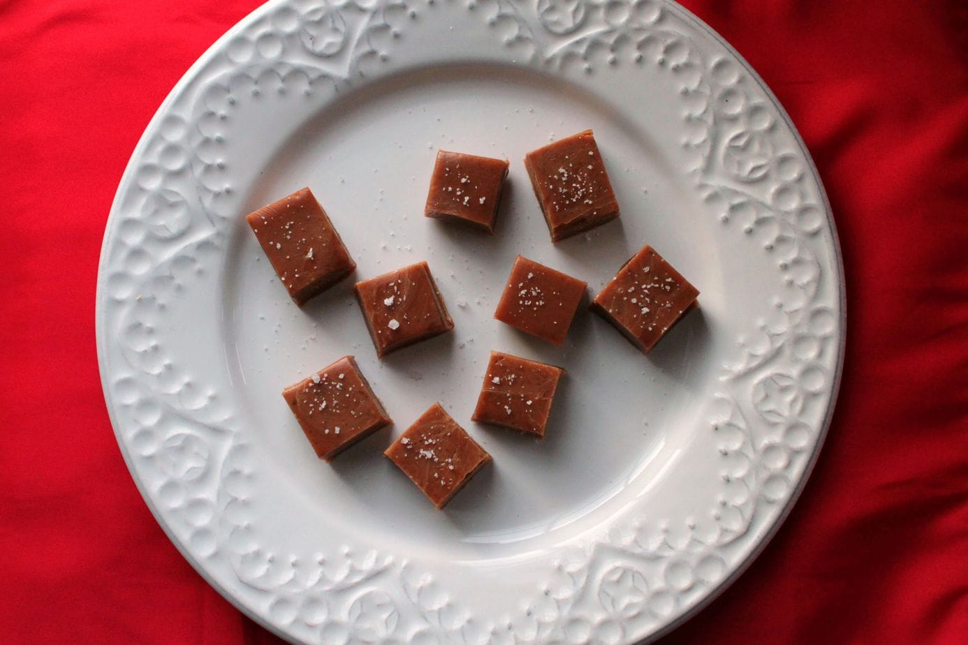 A white plate filled with Honey Jack Salted Caramels topped with coarse sea salt.