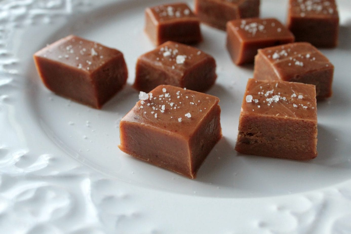 A white plate filled with Honey Jack Salted Caramels topped with coarse sea salt.