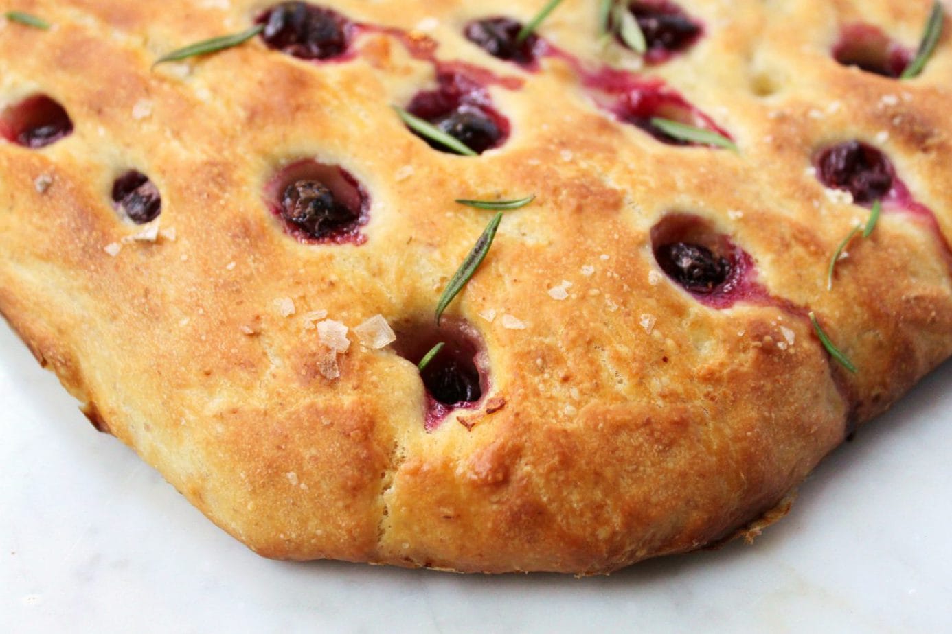 Golden baked sourdough focaccia with grapes and rosemary.