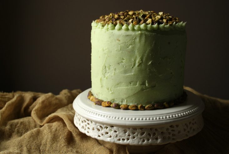 Chai Layer Cake with light green Pistachio Buttercream decorated with chopped pistachios.