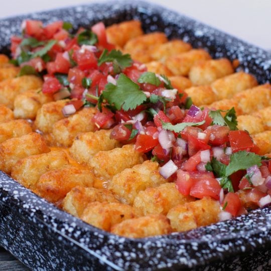 A casserole dish filled with a taco casserole topped with golden baked tater tots.