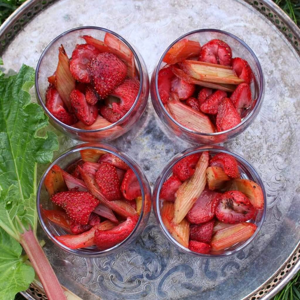 Strawberry Rhubarb Dessert in glasses on a silver tray with rhubarb stalks.