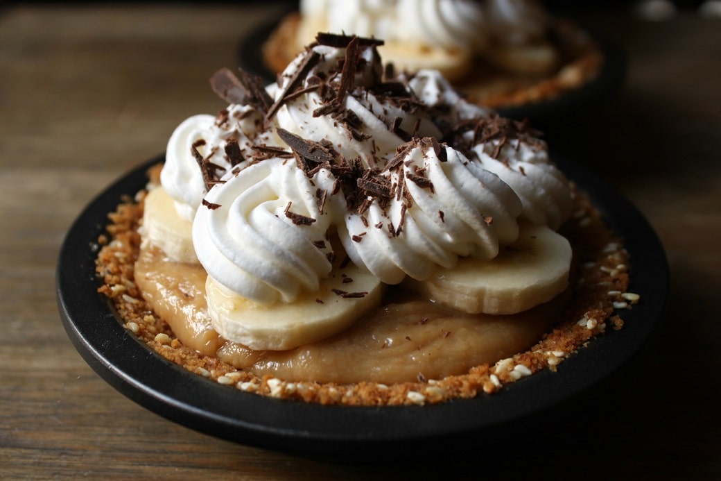 These mini Banoffee Pies feature the superb combination of bananas and caramel with a bit of rum thrown in for fun. The base has sesame seeds for a little nutty kick. For sweet tooths only! #banoffeepie #pie #banana #toffee #dessert