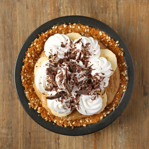 A mini banoffee pie topped with whipped cream and chocolate shards.