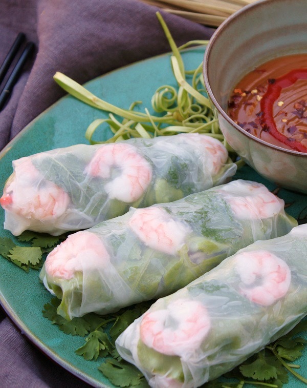 Three Vietnamese Shrimp Salad Rolls on a blue plate with a small bowl of peanut dipping sauce. 