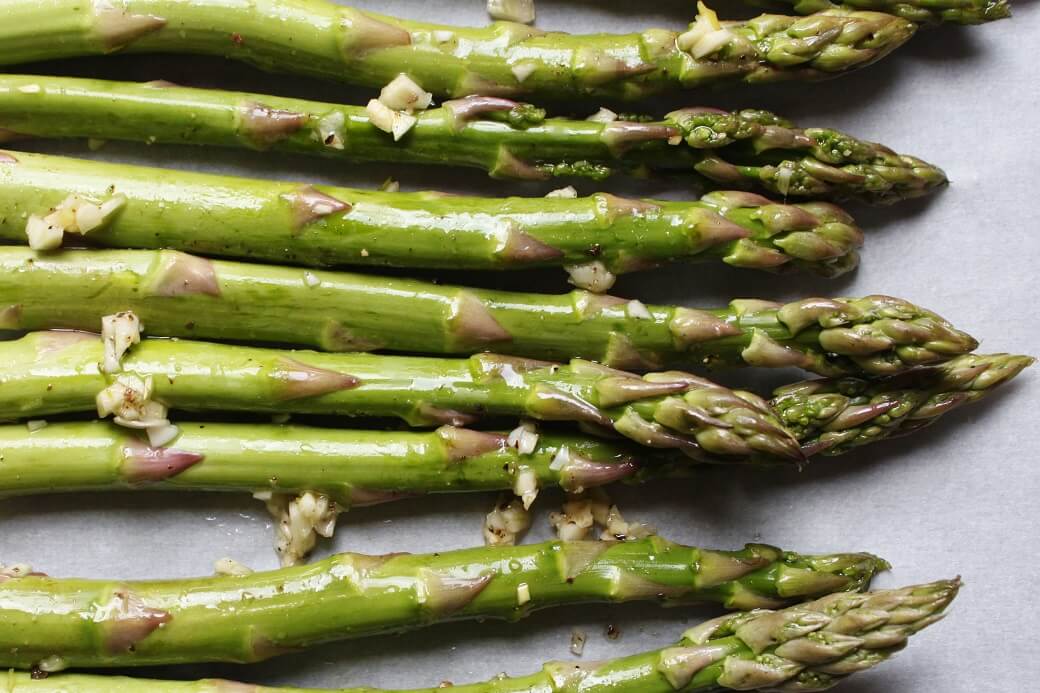 Close up photo of stalks of green asparagus and minced garlic.