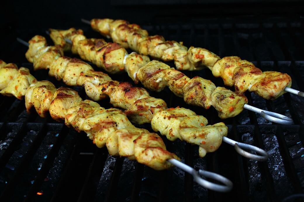Cooked turmeric marinated Chicken kabobs on a grill.