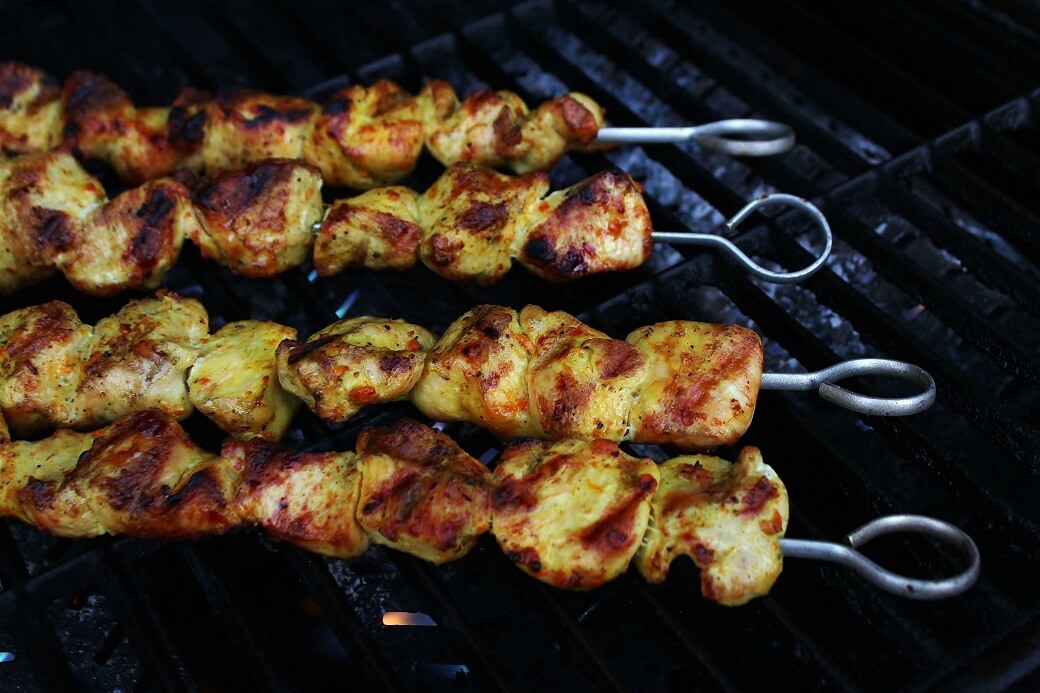 Cooked turmeric marinated Chicken skewers on a grill.