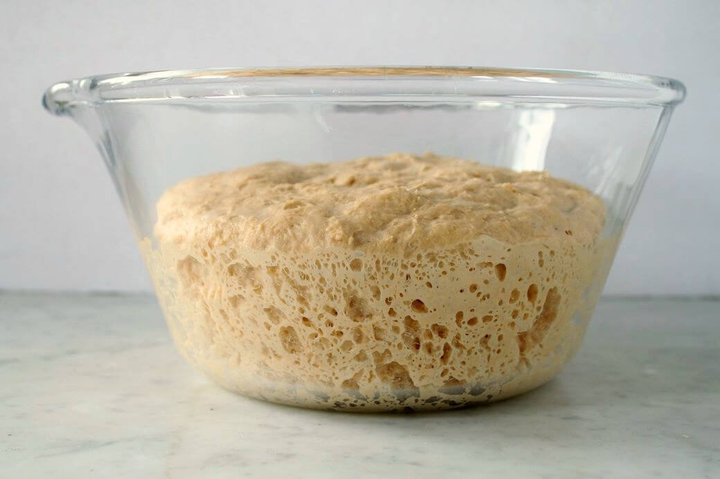 Pumpkin No Knead Bread -A clear glass bowl containing risen dough.