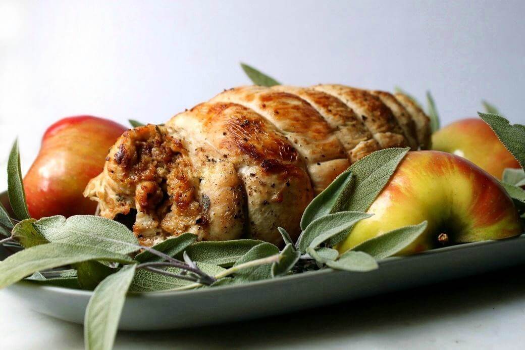 Apple Herb Stuffed Turkey Breast Recipe - Apple Herb Stuffed Turkey Breast Recipe - A whole stuffed Turkey breast on a platter surrounded by fresh sage and apples.