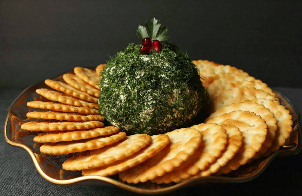 Dill Pickle Cheese ball - A cheese ball covered in fresh chopped dill sits in the middle of a circle of crackers.