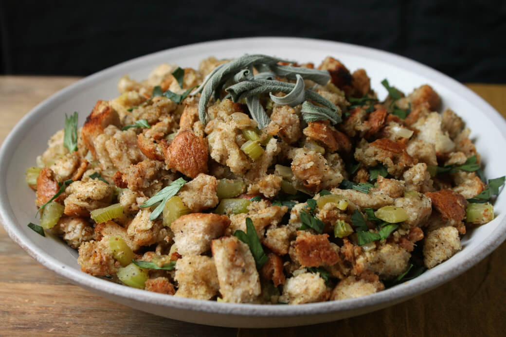 Homemade Stuffing Recipe featuring classic bread stuffing studded with onions and celery in a grey bowl.
