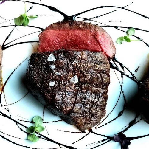 A perfectly cooked steak with a slice cut showing the degree of doneness. Where to Eat in Calgary