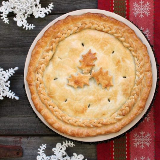 Christmas Eve Tourtière - A golden baked pie with braided pastry and holly design.