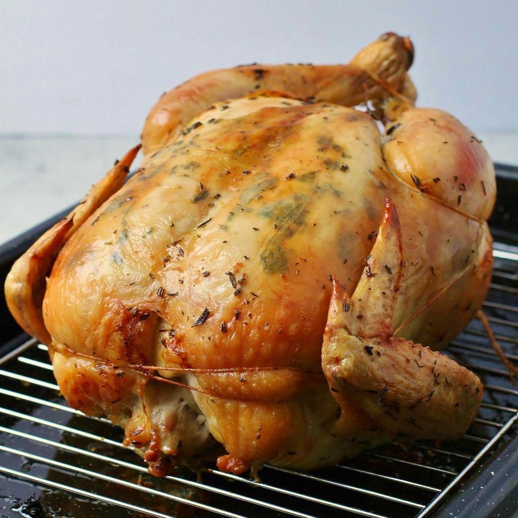 Dry Brine Chicken - A perfectly browned and roasted whole chicken sits inside a roasting pan.