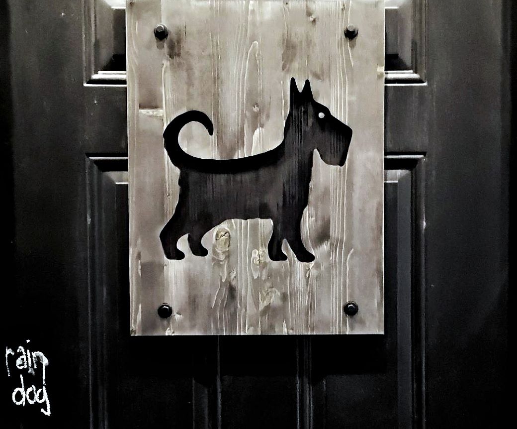 Rain Dog Bar - A black door with a dog shaped cut out.