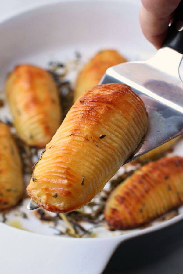 Crispy Herbed Hasselback Potatoes - Close up of crispy golden potatoes in a white baking dish.