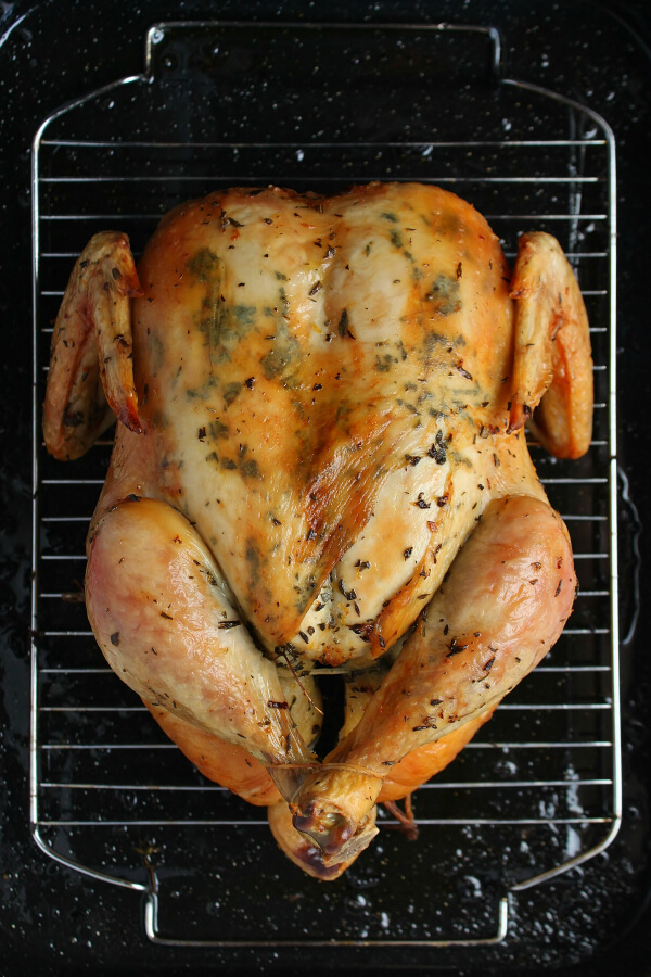Dry Brine Chicken - A perfectly browned and roasted whole chicken sits inside a roasting pan.