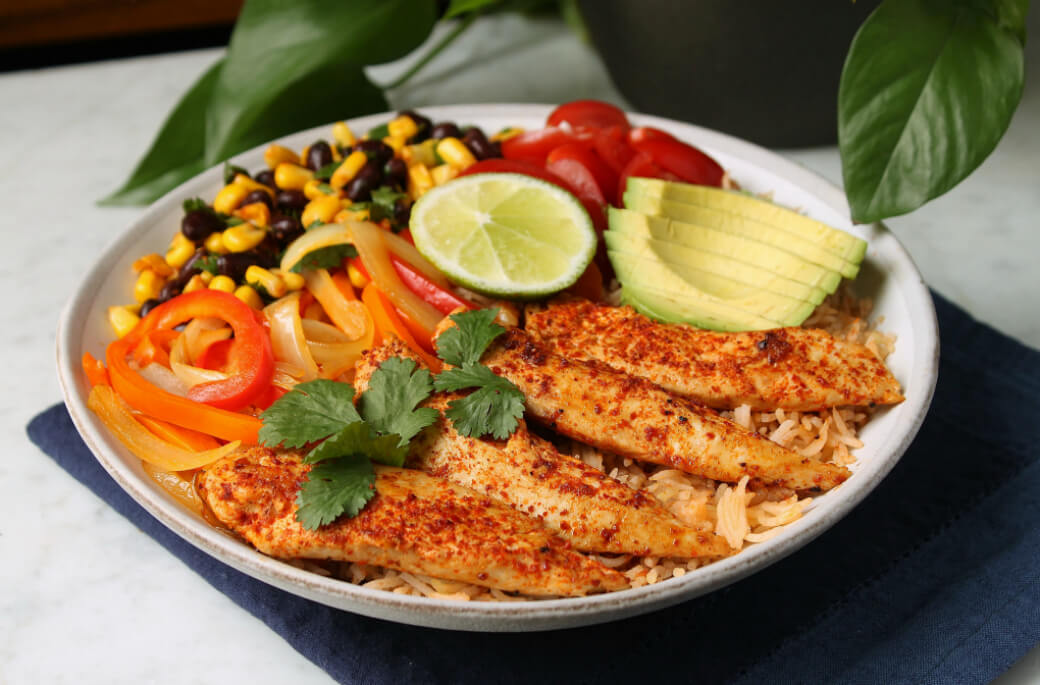 Simply Delicious Chicken Burrito Bowl - a bowl filled with chicken, rice, peppers, avocado, corn and beans.